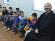 Pe. Luis Montes e crianças de um jardim de infância em um acampamento de refugiados no Iraque.