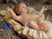 Menino Jesus com os braços abertos e os pés superpostos, como na Cruz