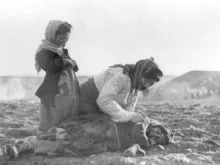 Uma mulher armênia ajoelhada diante de uma criança falecida pelo Genocídio Armênio.