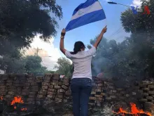 Jovem segura a bandeira da Nicarágua em meio aos protestos e repressão policial.