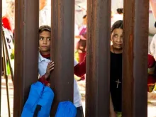 Crianças observam ato inter-religioso do lado mexicano do muro na fronteira.