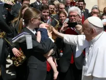 O papa saúda a filha de um membro da orquestra após a audiência geral.