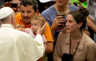 Papa abençoa uma criança ao chegar à Sala Paulo VI.