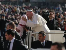 Papa Francisco beija um bebê na Praça de São Pedro.