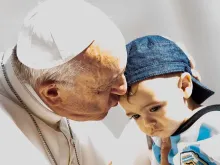 Papa Francisco beija uma criança na Praça de São Pedro.
