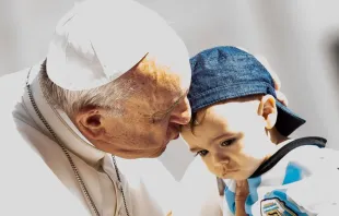 Papa Francisco beija uma criança na Praça de São Pedro.