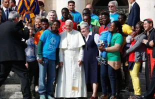 Papa tira uma foto com alguns imigrantes na Praça de São Pedro.