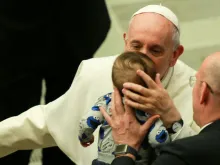 O Papa Francisco beija um menino no Sala Paulo VI.