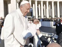 Papa abençoa uma criança em uma Audiência Geral.