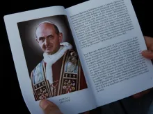 Um fiel participa da Missa de canonização e mostra a imagem de São Paulo VI no folheto preparado para a ocasião.