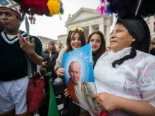 Um grupo de peregrinos segura uma imagem de São João Paulo II na Praça de São Pedro