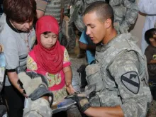 Soldado americano entrega material escolar para crianças no Iraque.
