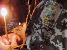 Militar ucraniano reza com vela na mão