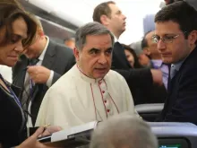 O arcebispo Angelo Becciu fala com jornalistas a bordo do voo papal para Colombo.