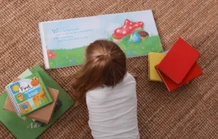 Menina da educação infantil lendo um livro na creche