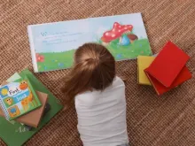 Menina da educação infantil lendo um livro na creche