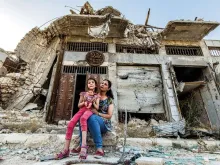 Família na Síria diante de escombros.